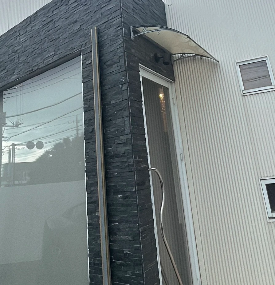 黒い石張りの壁とひさしが目印のサロン入口